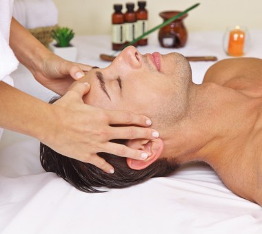 Entspannter Mann im Day Spa bekommt eine Massage am Kopf
